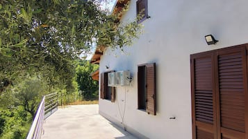 Un bâtiment à la façade blanche, aux volets bruns et doté d’un climatiseur fixé au mur.
