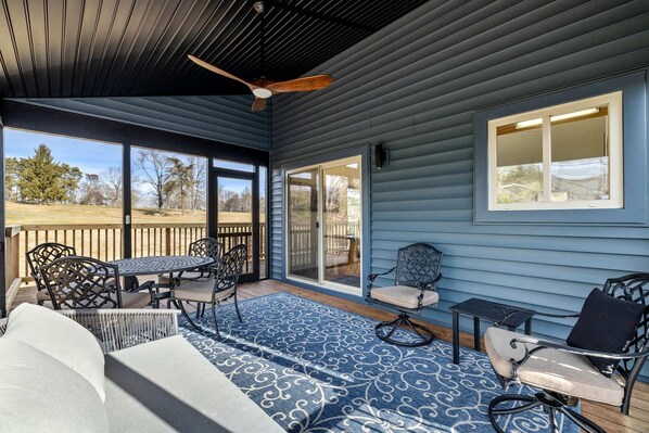 A covered patio with a table and chairs, a ceiling fan, and a view of the outdoors.