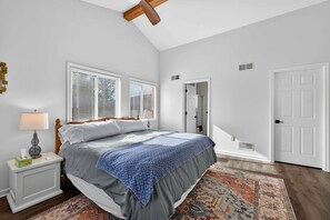 A bedroom with a bed, nightstand, lamp, and a patterned rug.