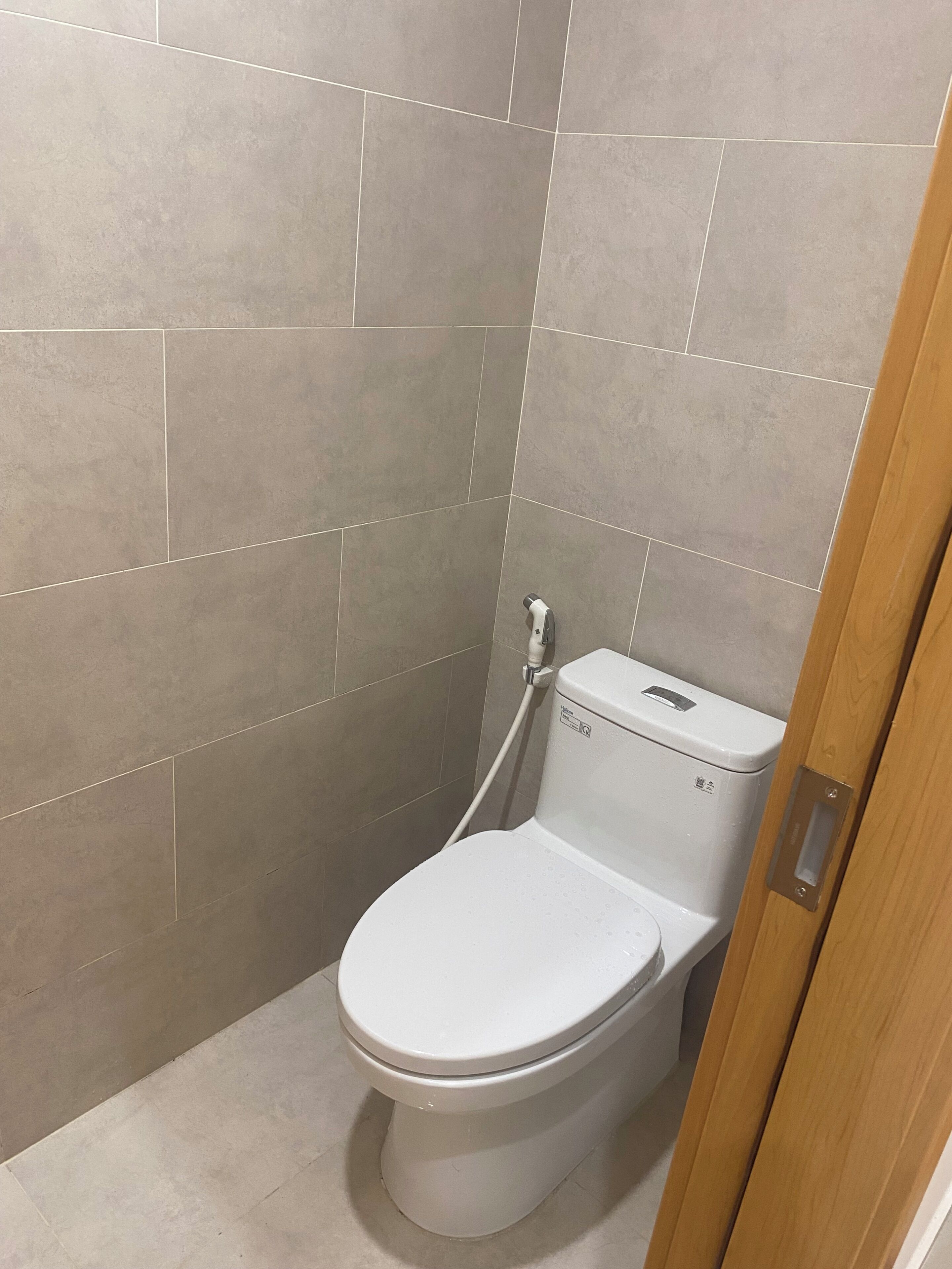 Ein kleines, modernes Badezimmer mit Toilette, Dusche und gefliesten Wänden.