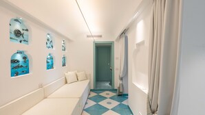 A narrow hallway with a bench, a teal and white tiled floor, and wall-mounted artwork. - Estate4home - Villa Nerea (Massa Lubrense)