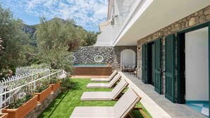 A poolside area with lounge chairs, a stone wall, and a view of the mountains. - Estate4home - Villa Nerea (Massa Lubrense)