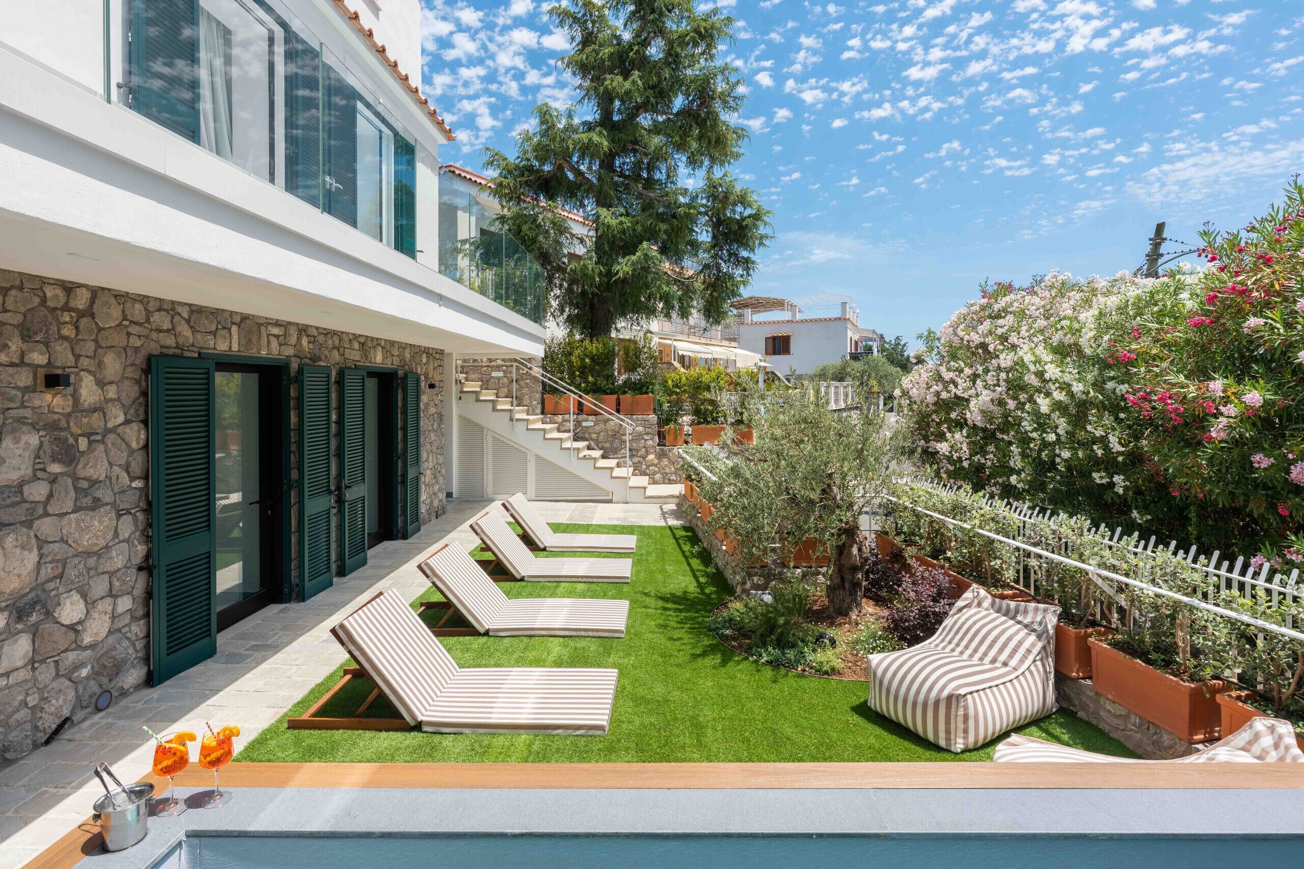 Eine moderne Villa mit Pool, Sitzgelegenheiten im Freien und einer Steinmauer.