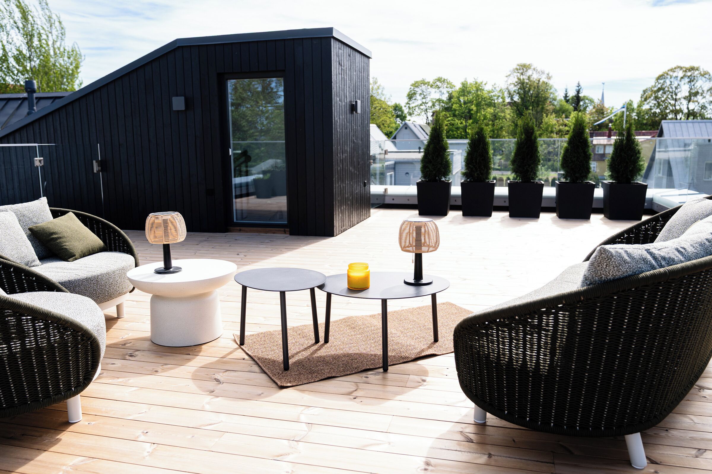 A modern outdoor seating area with wicker furniture, a glass door, and potted plants.