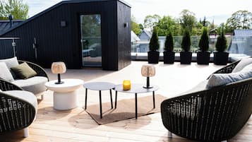 A modern outdoor seating area with wicker furniture, a glass door, and potted plants.