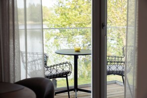 A balcony with a table and chairs, a view of trees and water, and a door leading to another room. - Jaanson Captain Penthouse I Free Sauna & Parking (Pärnu)