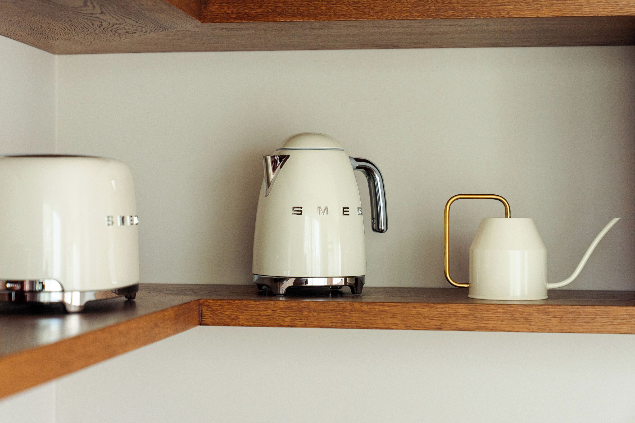 Un plan de travail de cuisine avec un grille-pain, une bouilloire électrique blanche et une cafetière blanche avec un manche doré.