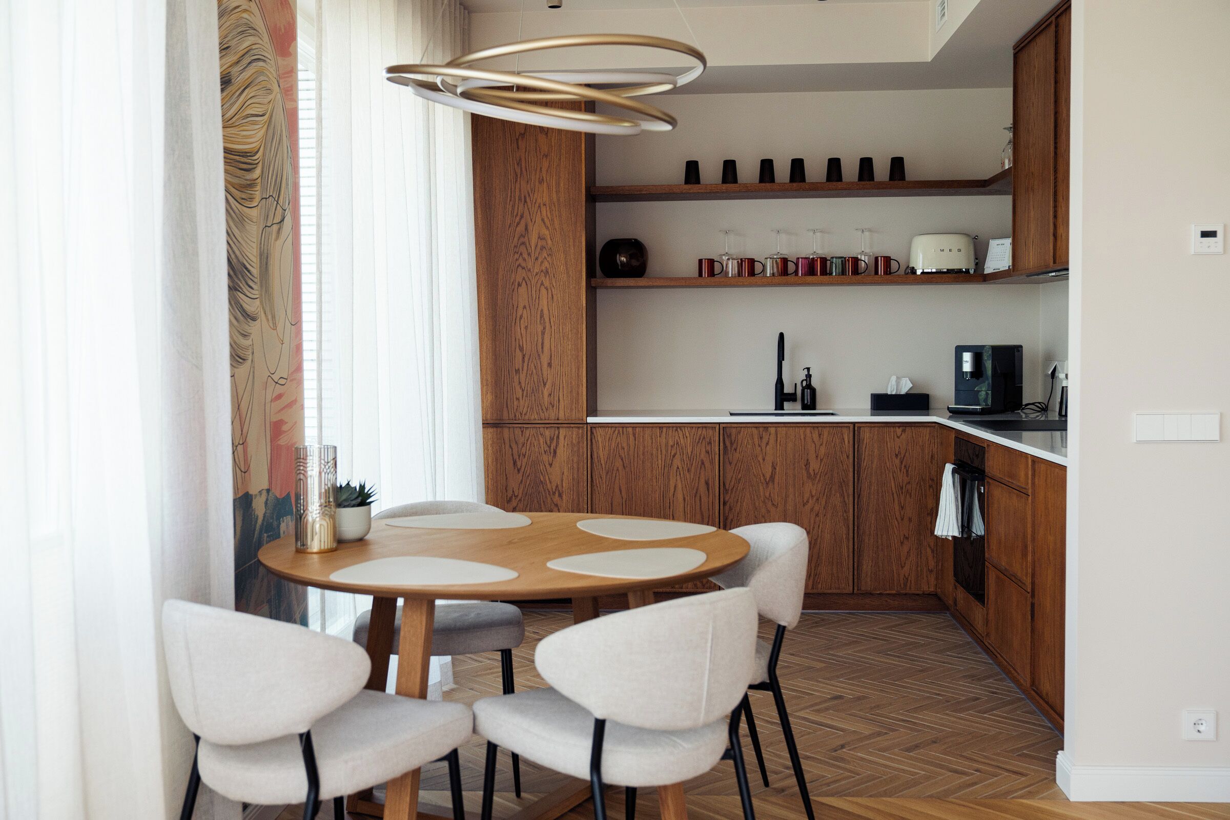 A modern kitchen with wooden cabinets, a round dining table with chairs, and a pendant light fixture.