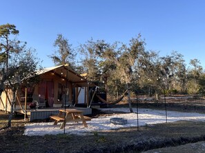 A wooden cabin with a porch, a dining table, and a fire pit.