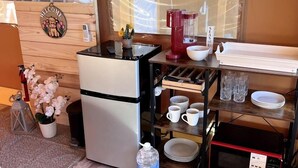 Et kompakt køkken med et køleskab, en mikrobølgeovn og en kaffemaskine på en træbordplade.
