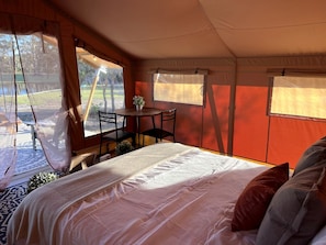 A tent with a bed, a table, and chairs.