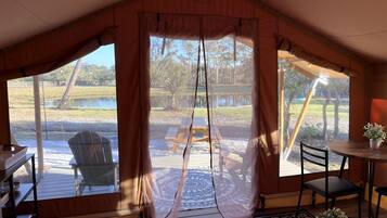 A tent with a view of a picnic table and chairs outside.