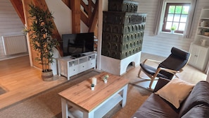 A living room with a TV, a sofa, a wooden coffee table, a potted plant, and a decorative cabinet.