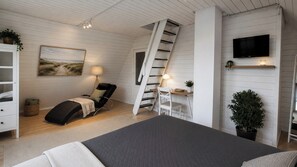 Une chambre avec un lit, un bureau, une chaise, une échelle, un téléviseur et une plante.