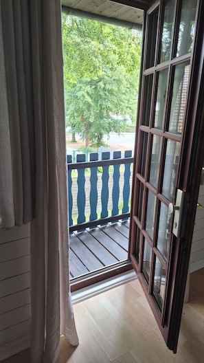 A room with a sliding glass door leading to an outdoor balcony with a blue railing.