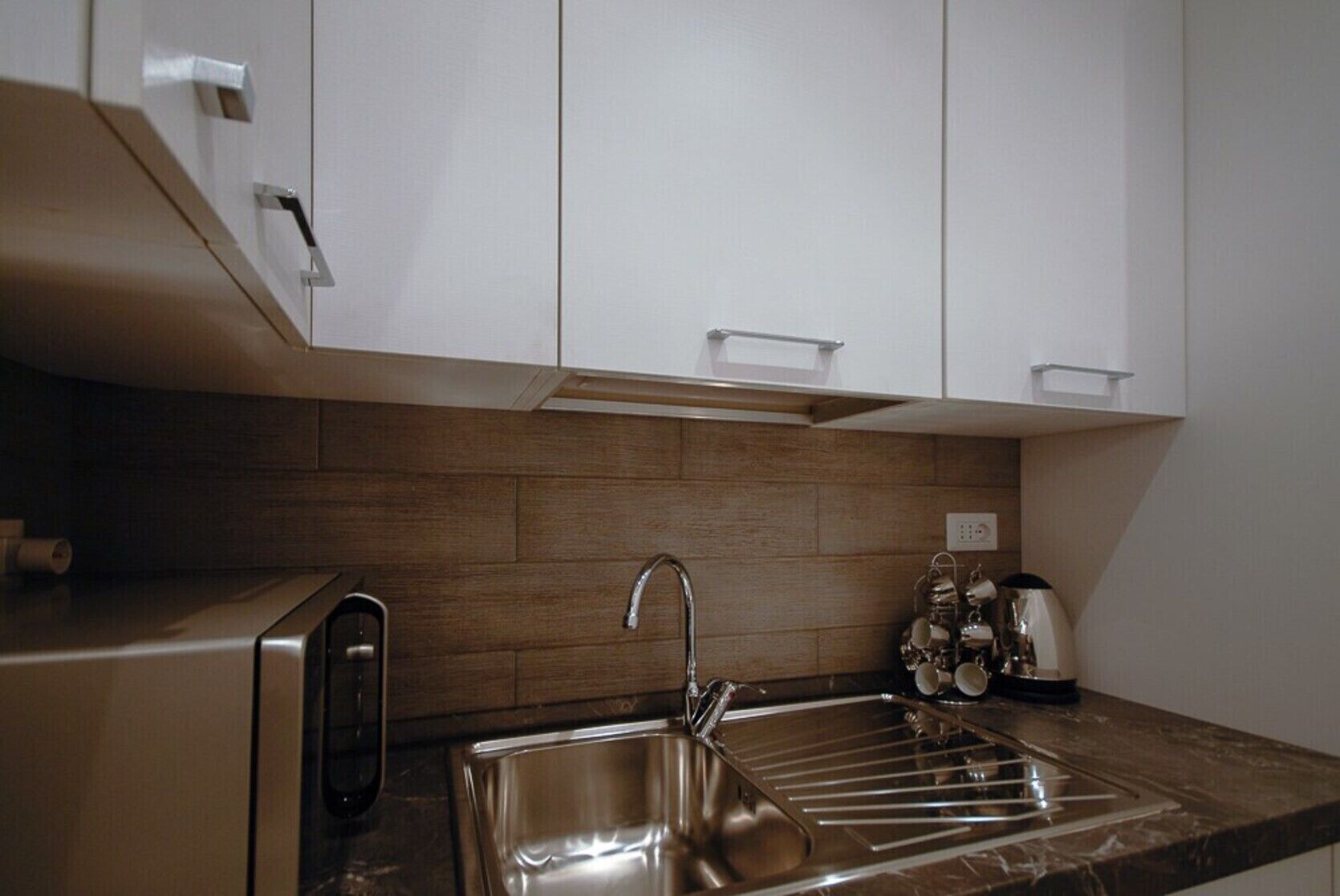 A modern kitchen with stainless steel appliances, a sink, and wooden backsplash.