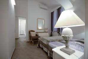 A bedroom with a bed, a chair, a dresser, a mirror, and a lamp. - Colosseo & Fori Imperiali Apartment (Rome)