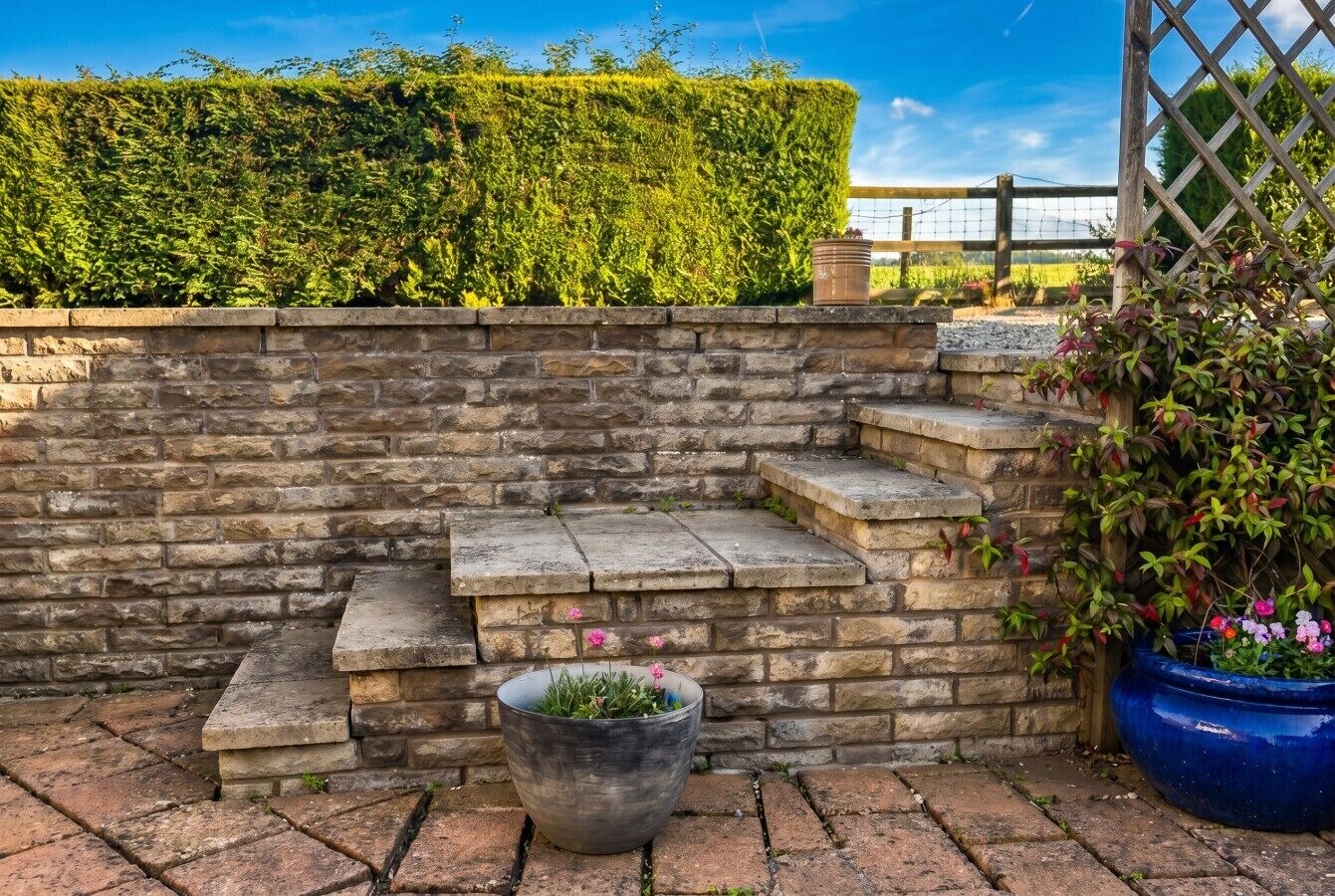 Stone steps and potted colour lead up to the countryside edge