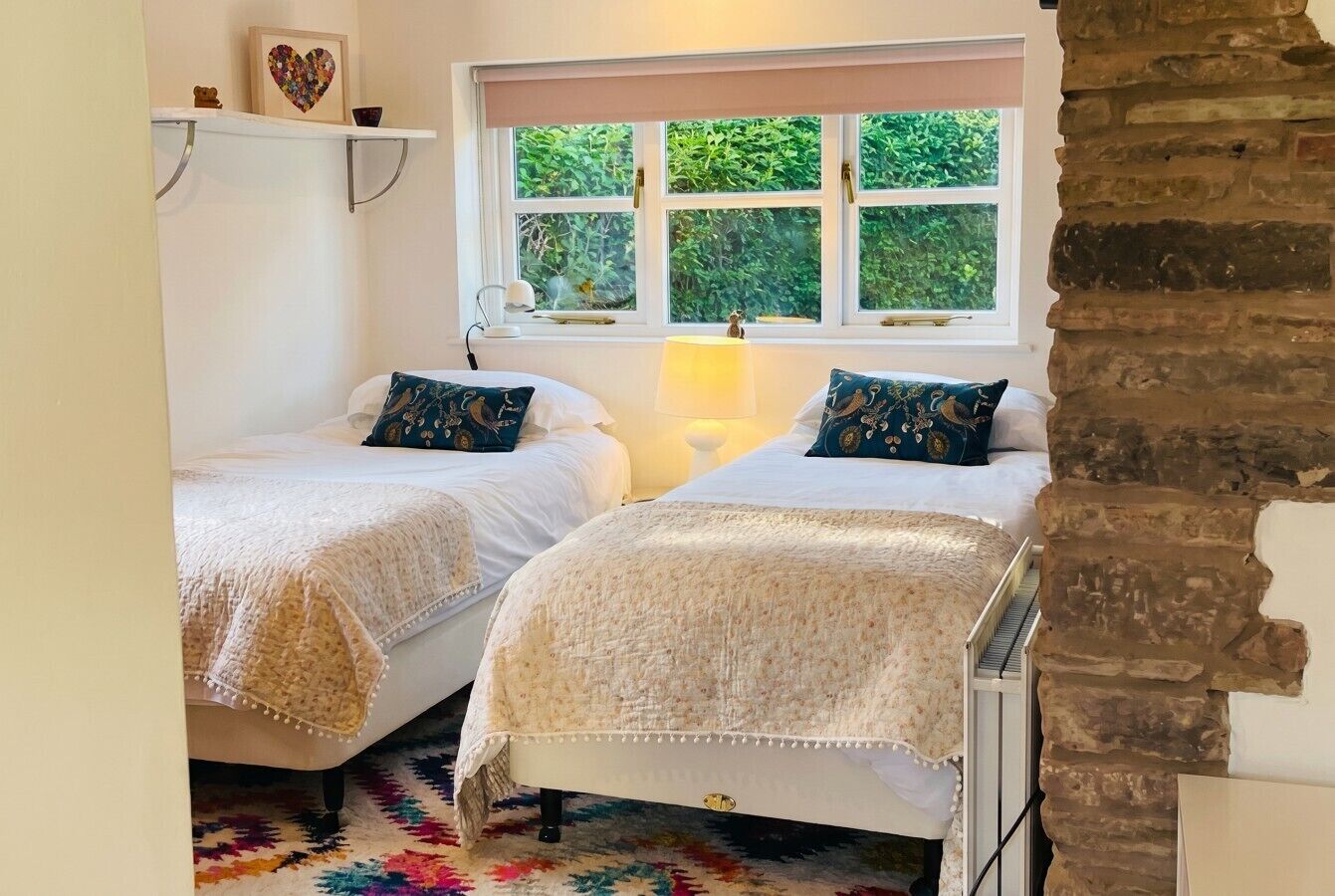 Characterful twin bedroom blending original brickwork with garden light
