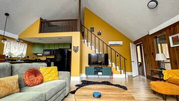 A living room with a sofa, coffee table, and a television.