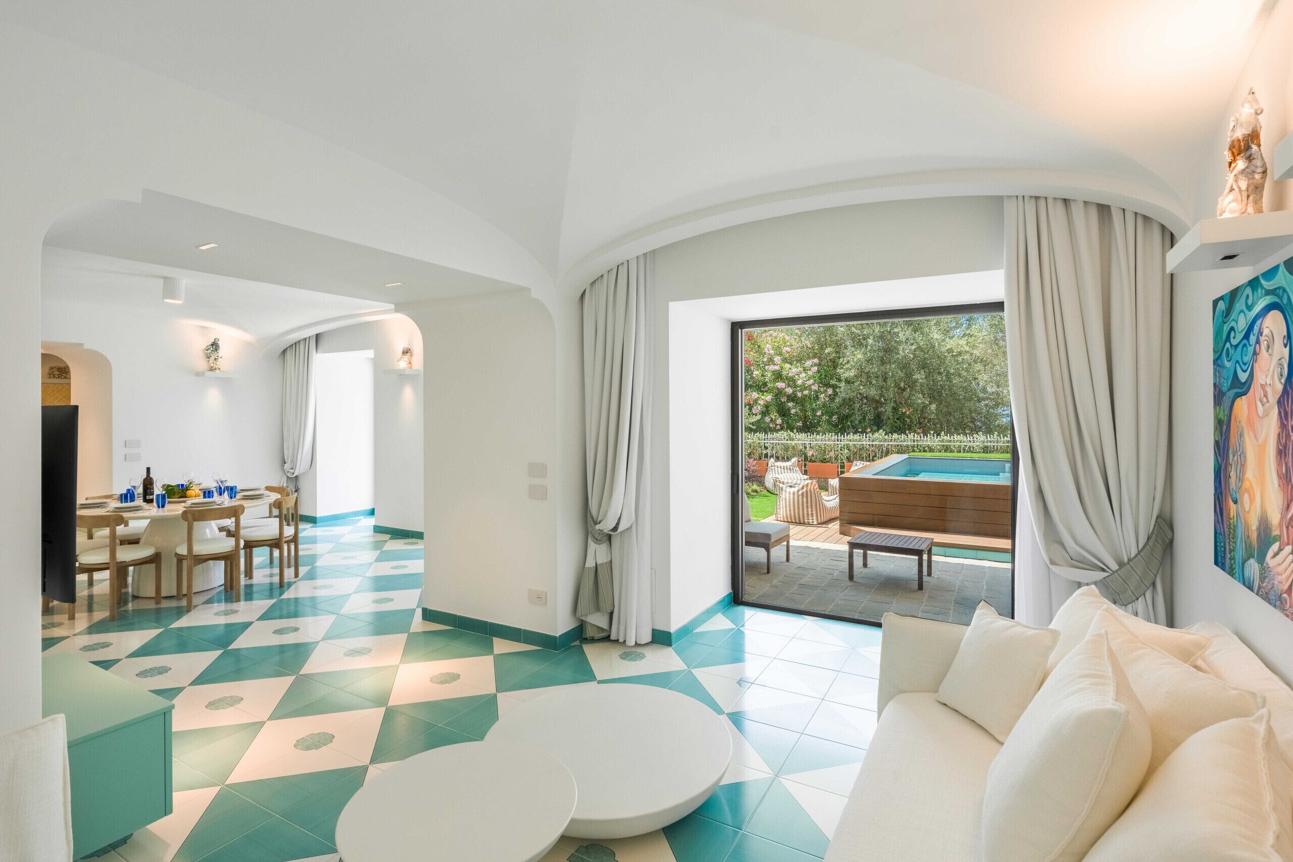 Un interior moderno con comedor, sala de estar con sofá y vista a una piscina exterior.