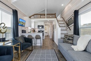 A modern interior with a living area, kitchen, and a staircase leading to an upper level. - Luxury Hill Country Tiny Home in Resort Setting Near Fredericksburg, Texas (Fredericksburg)