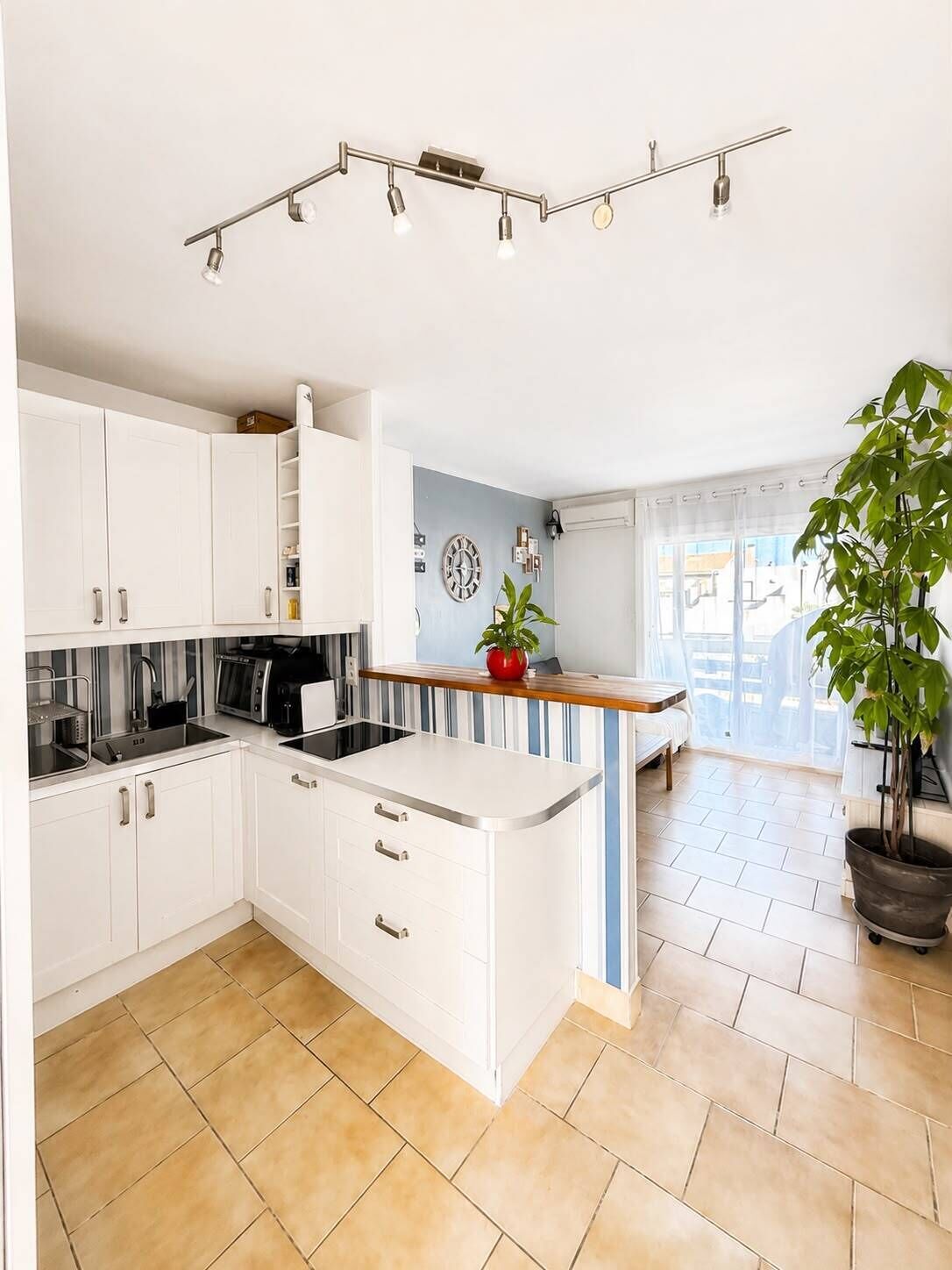 A modern kitchen with white cabinetry, a central island, and a dining area with a view.