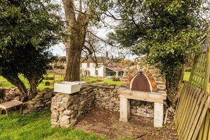 Une construction en pierre, dotée d’un banc en bois et d’un mur en pierre.