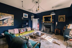 A living room with a sofa, a fireplace, and a chandelier. - Lavish Farmhouse with Lake access, Gardens & Pool Table (Oakhill)