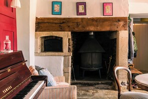 A cozy room with a piano, a fireplace, and framed artwork on the wall. - Lavish Farmhouse with Lake access, Gardens & Pool Table (Oakhill)