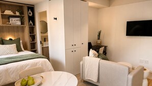 Ein modernes Schlafzimmer mit Bett, einer Sitzecke, einem Fernseher und einem Kleiderschrank.