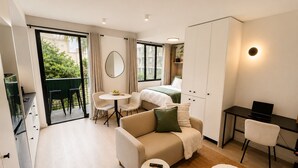 Ein modernes Hotelzimmer mit Sofa, Esstisch, Bett und Schreibtisch.