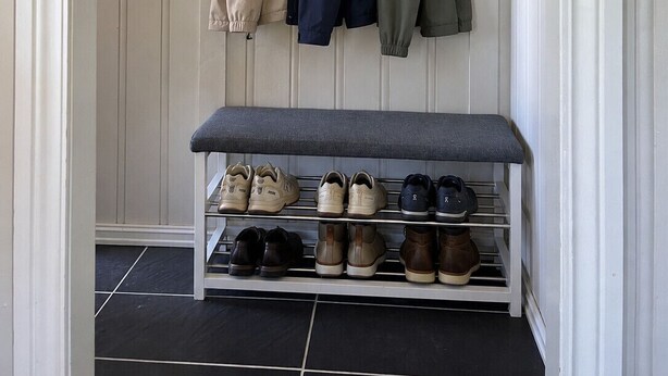 A hallway with a bench and a shoe rack.