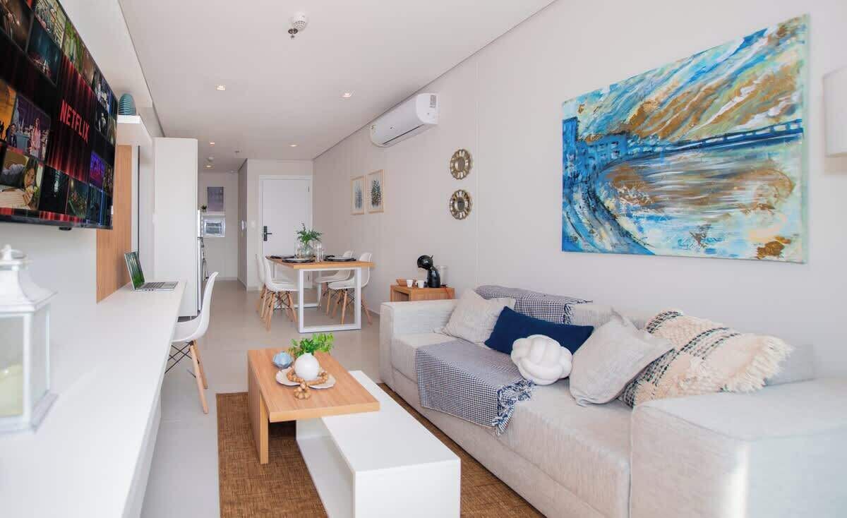 Ett modernt vardagsrum med en vit soffa, ett soffbord och en tv som är monterad på väggen.