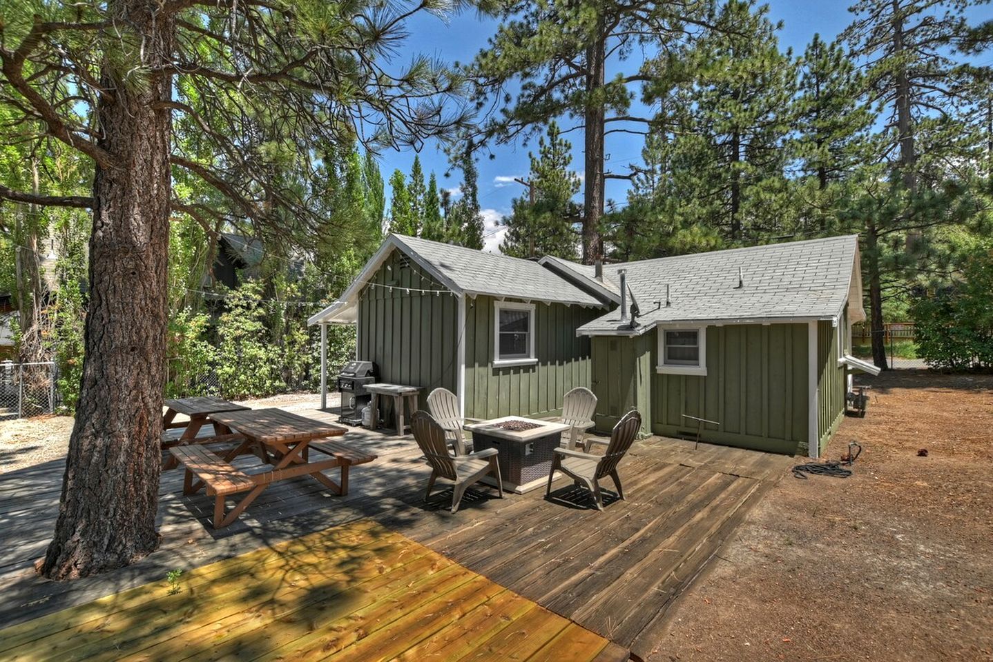 A cabin with a deck, picnic table, and chairs.