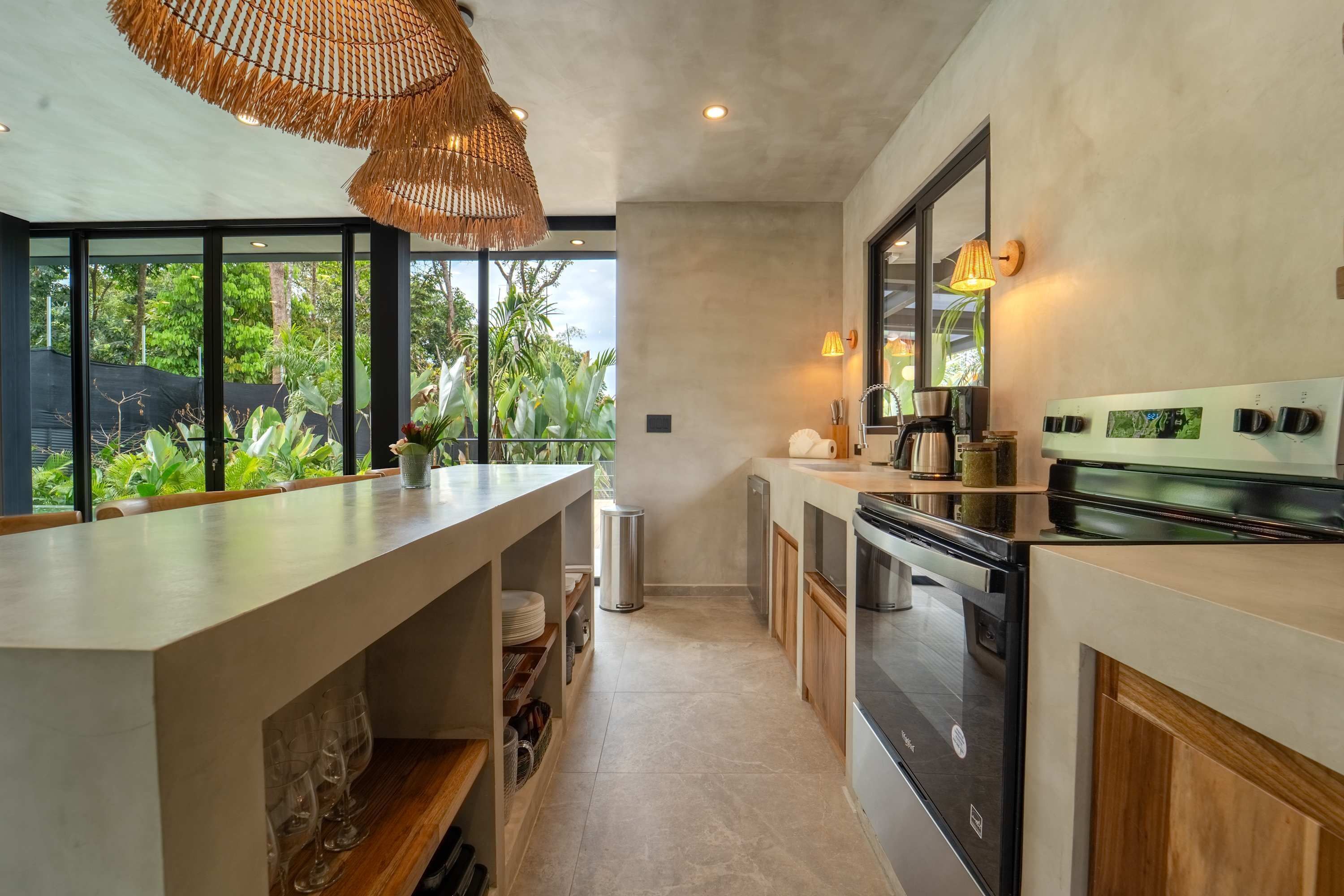 A modern kitchen with a large island, built-in appliances, and a view of greenery outside.