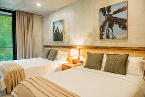 Quarto de hotel com duas camas, uma mesa de cabeceira com abajur e duas imagens emolduradas na parede.