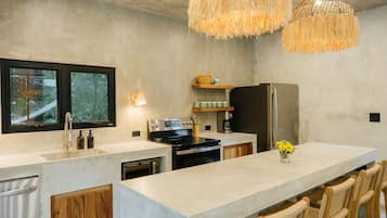 Uma cozinha moderna com uma ilha grande, eletrodomésticos embutidos e um lustre.