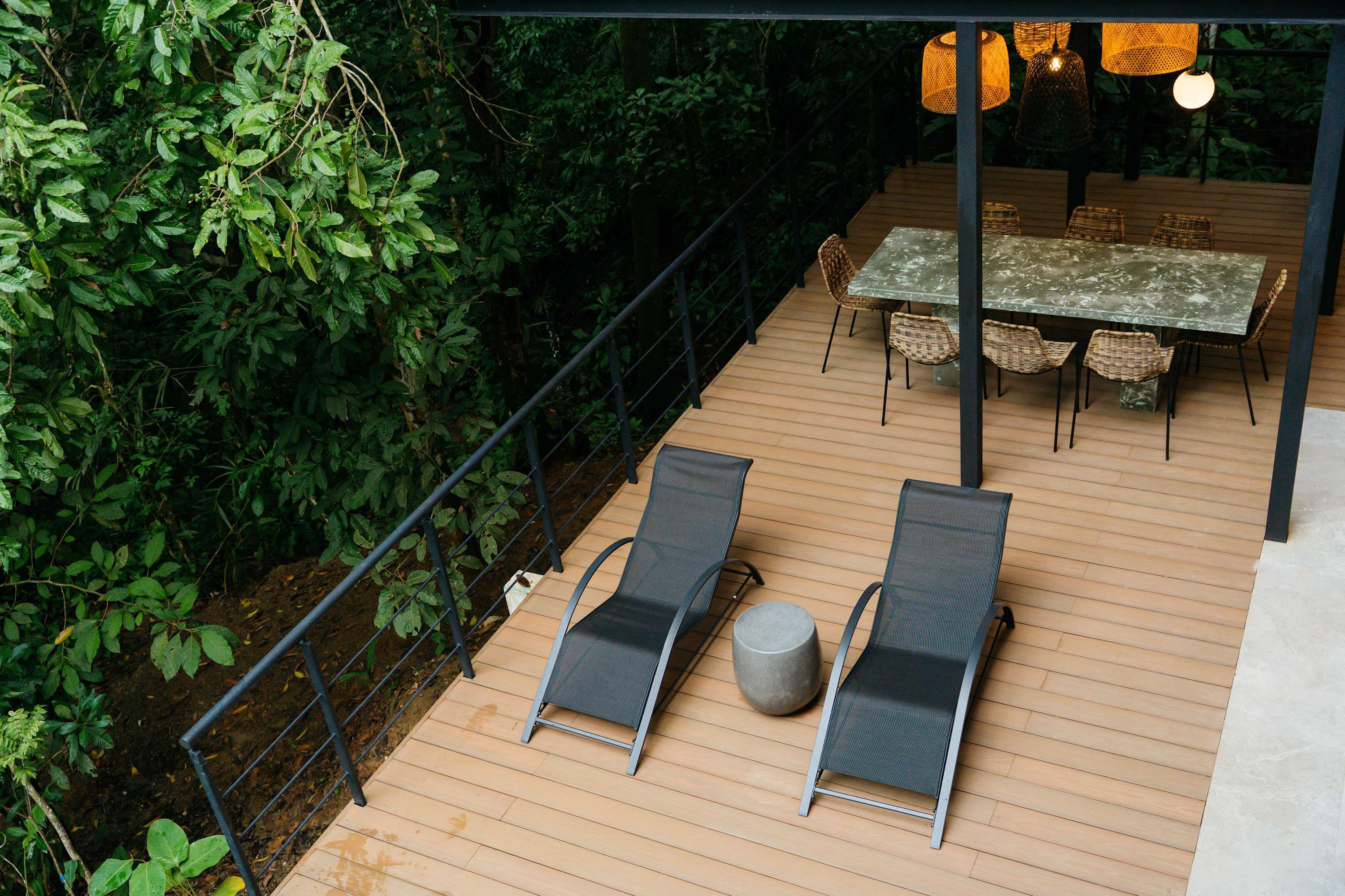 An outdoor deck with a table and chairs, surrounded by dense foliage.