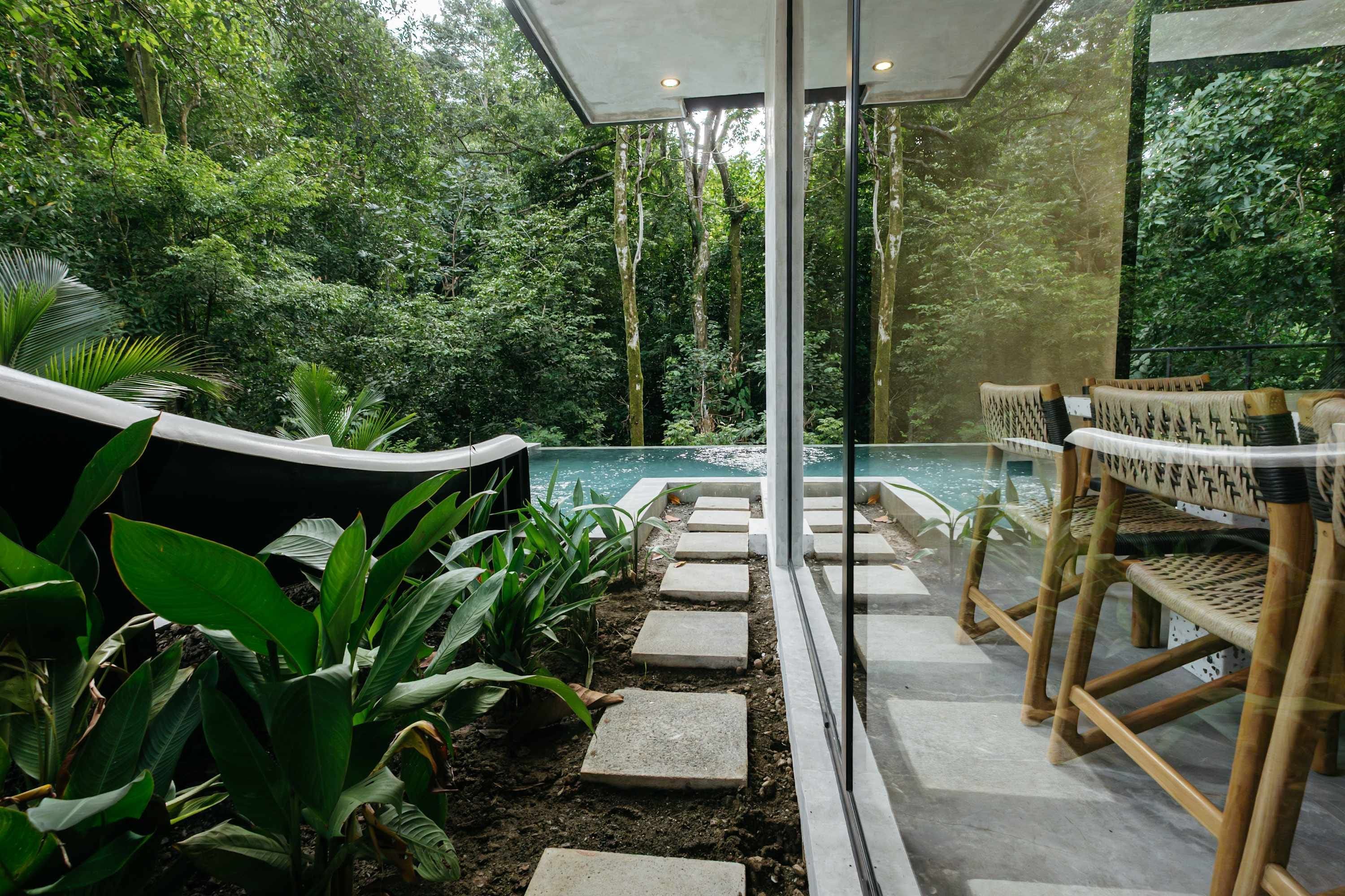 A pool area with stone steps leading to the water, surrounded by lush greenery and modern seating.