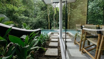 A pool area with stone steps leading to the water, surrounded by lush greenery and modern seating.
