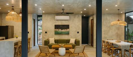 A modern interior with a dining area, a sofa set, and a painting on the wall.