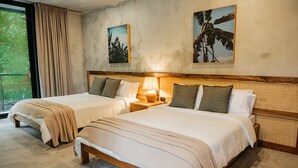 Ett hotellrum med två sängar, ett stort fönster med gardiner och konstverk på väggarna.