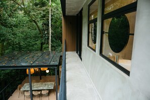 An outdoor dining area with a table and chairs, surrounded by a wooden deck and foliage. - New Private 3BR Luxury Tree House With Slide (Quepos)