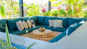 Ein grünes Ecksofa mit vielen Kissen, einem runden Holztisch und einer Vase.