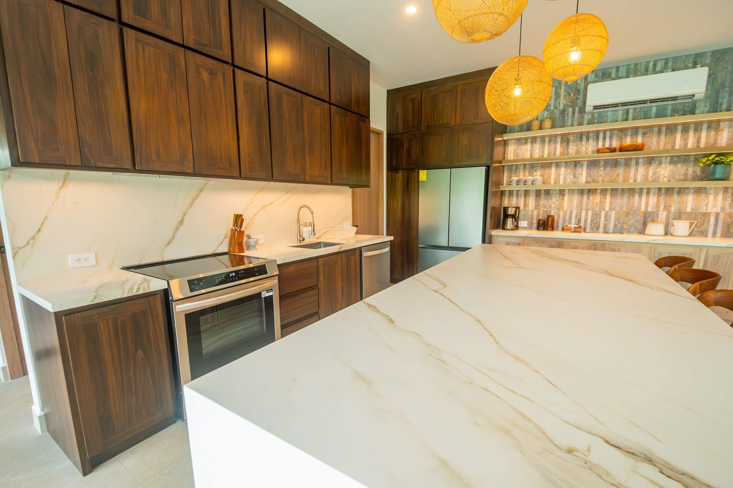 A modern kitchen with dark wood cabinets, a large marble countertop, and a built-in oven.