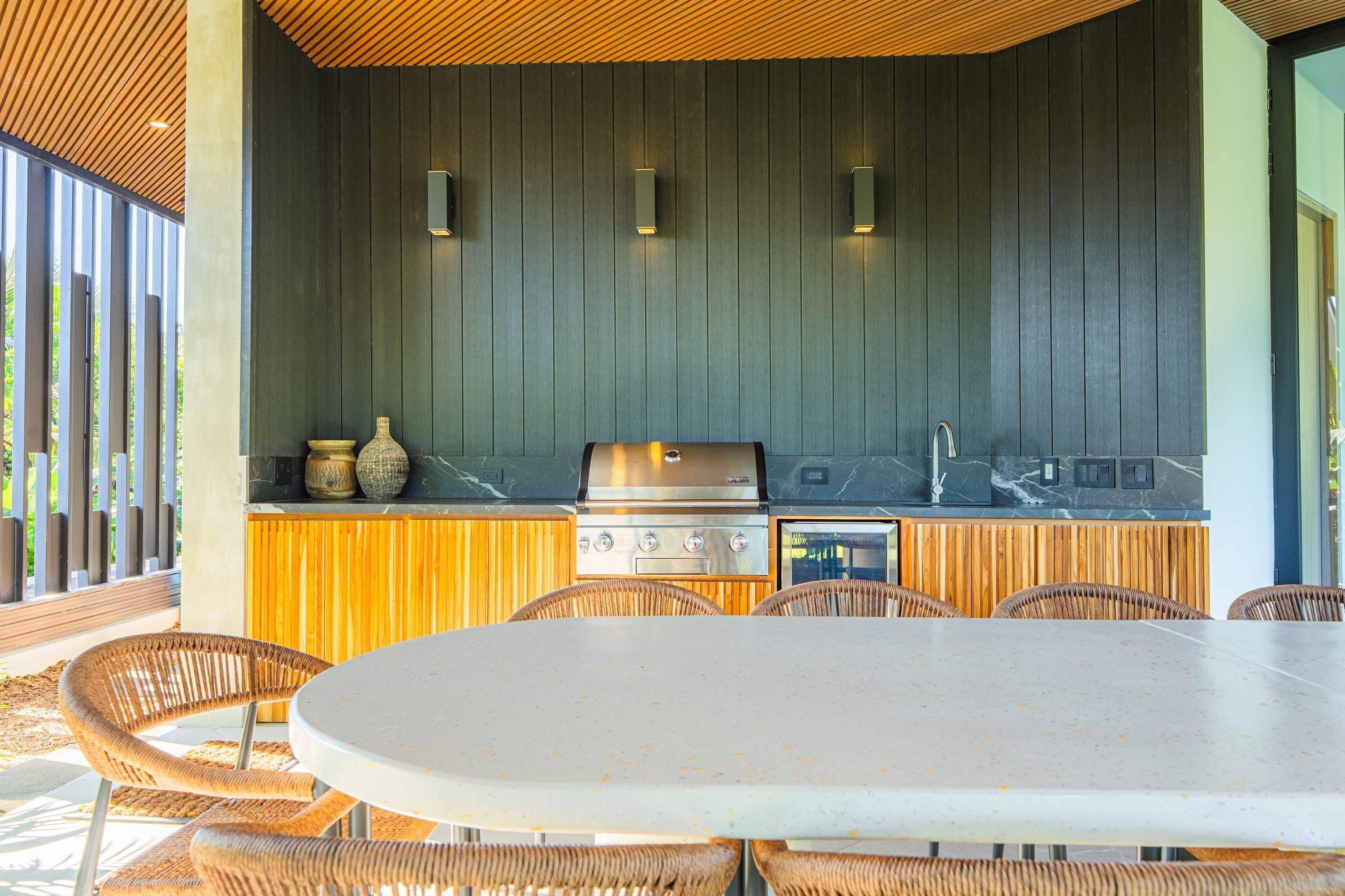 An outdoor kitchen area with a grill, built-in oven, and bar seating.