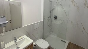 A modern bathroom with a glass-enclosed shower, a white sink, and a toilet. - LINDA affittacamere (ANCONA)