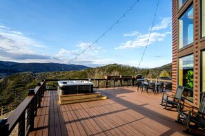 Eine Holzterrasse mit Whirlpool, Sitzgelegenheit und Blick auf die Berge.