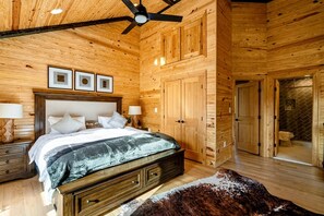 Ein Holzinterieur mit einem Bett, Nachttischen und einem Deckenventilator.